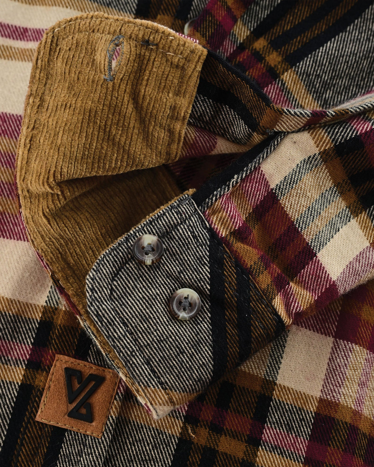 Close-up of a Cedarwood Plaid flannel cuff with tan corduroy lining, two adjustment buttons and stitched buttonhole