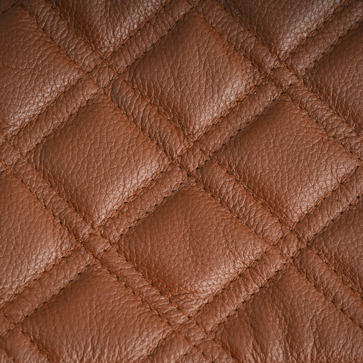 Close-up of cross-stitched diamond quilting and textured cognac brown cowhide leather on the motorcycle club vest