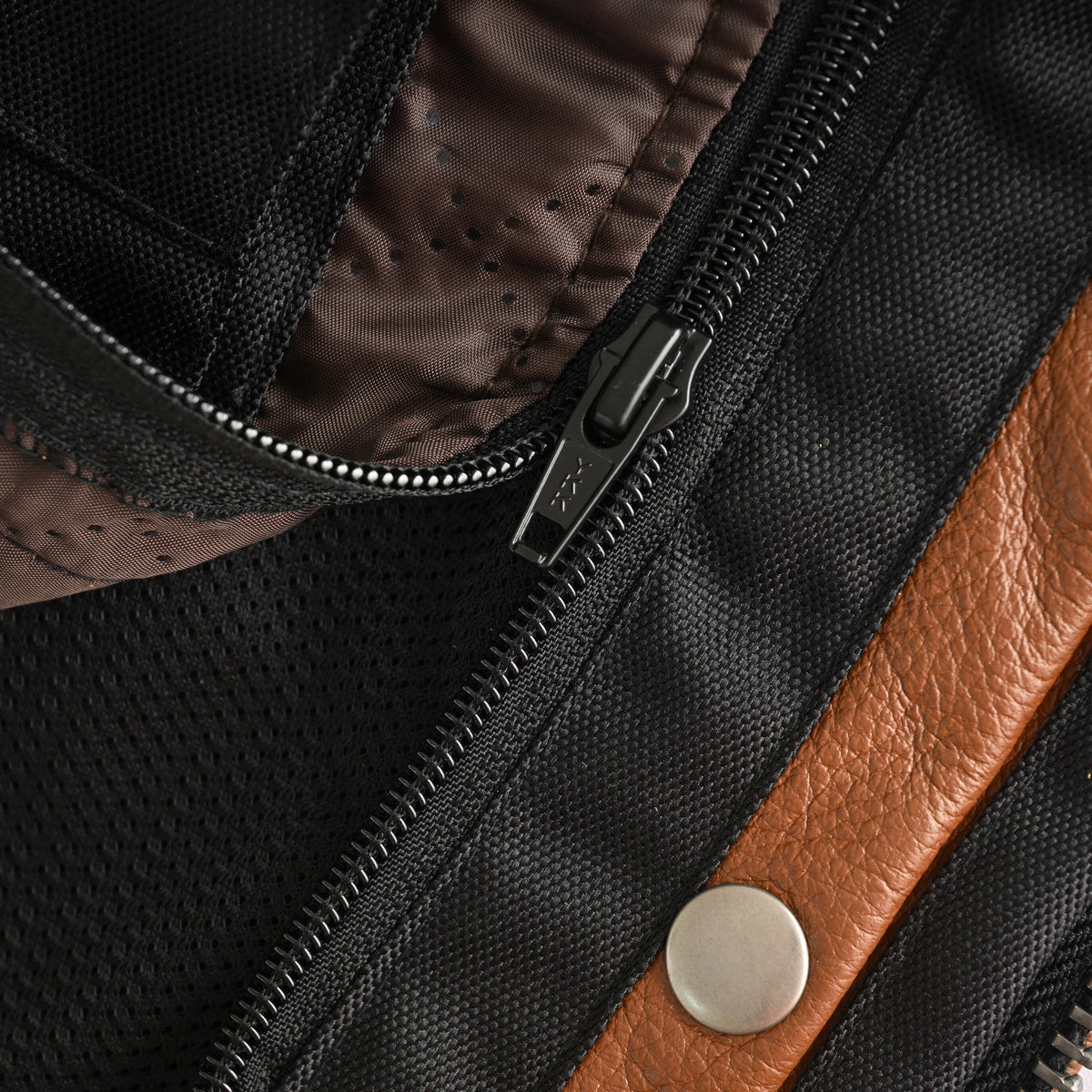 Close-up of the motorcycle jacket's removable quilted thermal liner, attachment zipper, and adjacent leather pocket trim.