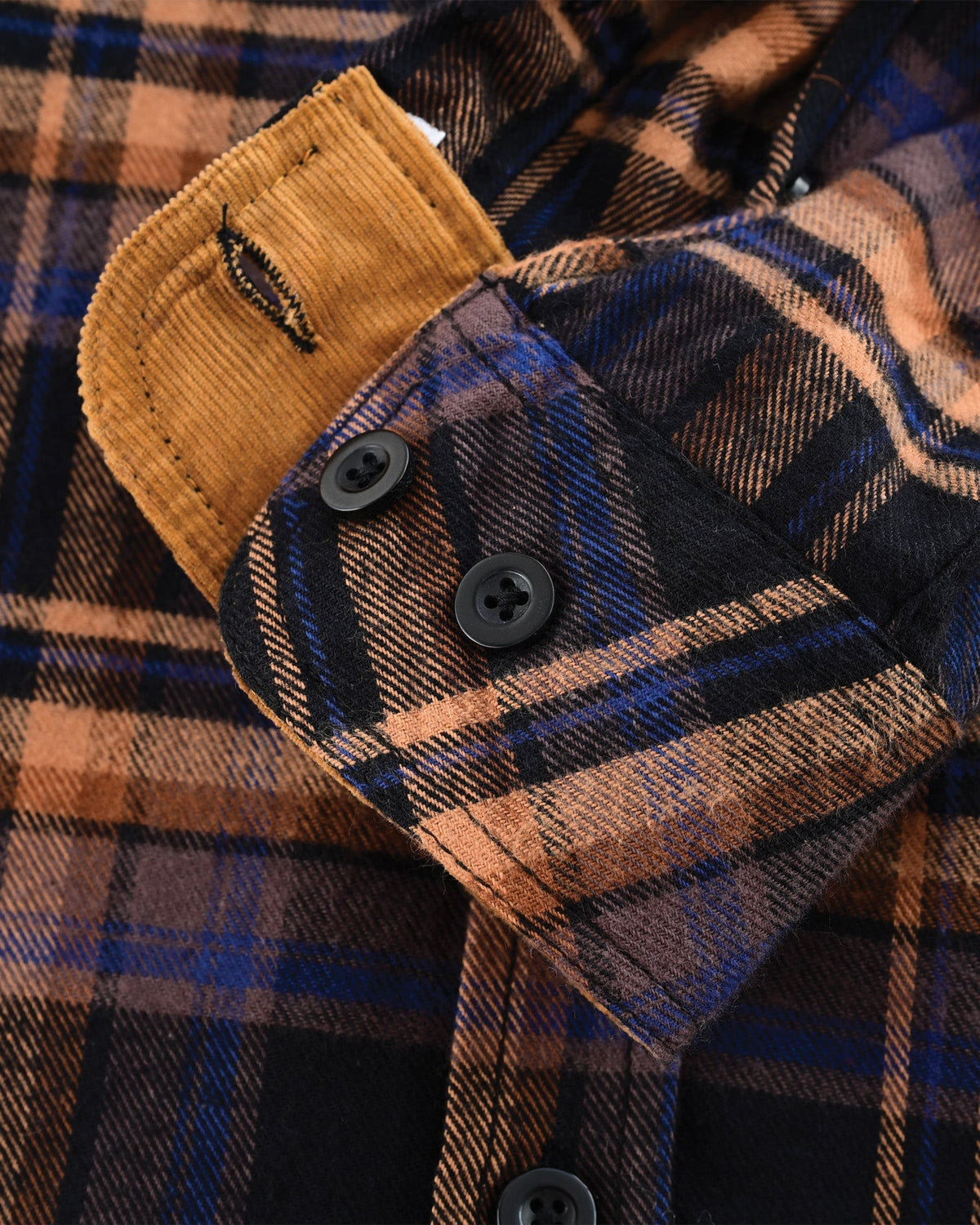 Close-up of the Midnight Rust flannel shirt's plaid cuff with two adjustment buttons and tan corduroy lining.