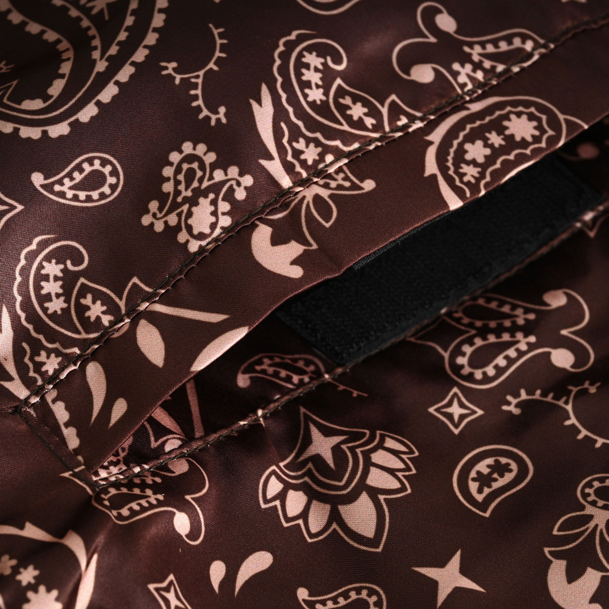 Close-up of an interior pocket opening with black hook-and-loop fastening beneath the brown paisley motorcycle vest lining.