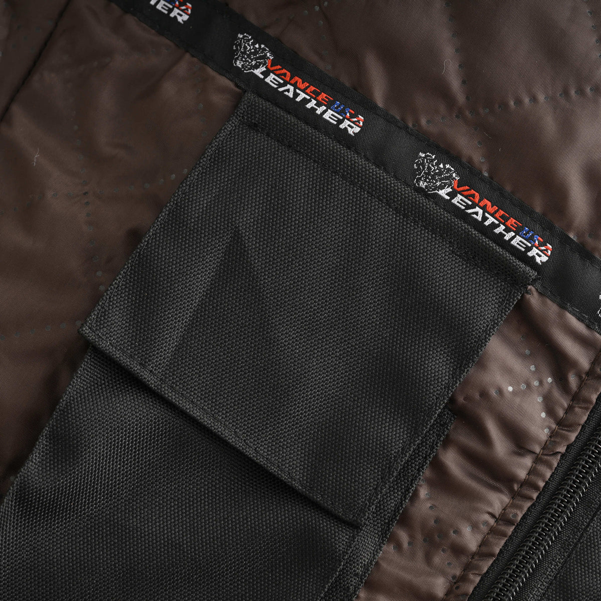 Close-up of a black interior accessory pocket with a flap closure against the motorcycle jacket's brown lining.