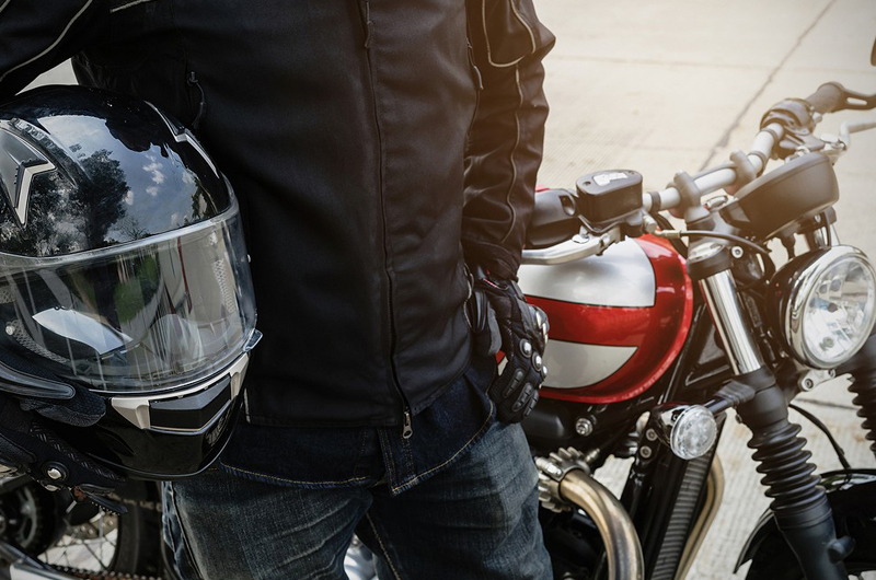 A rider holding a motorcycle helmet